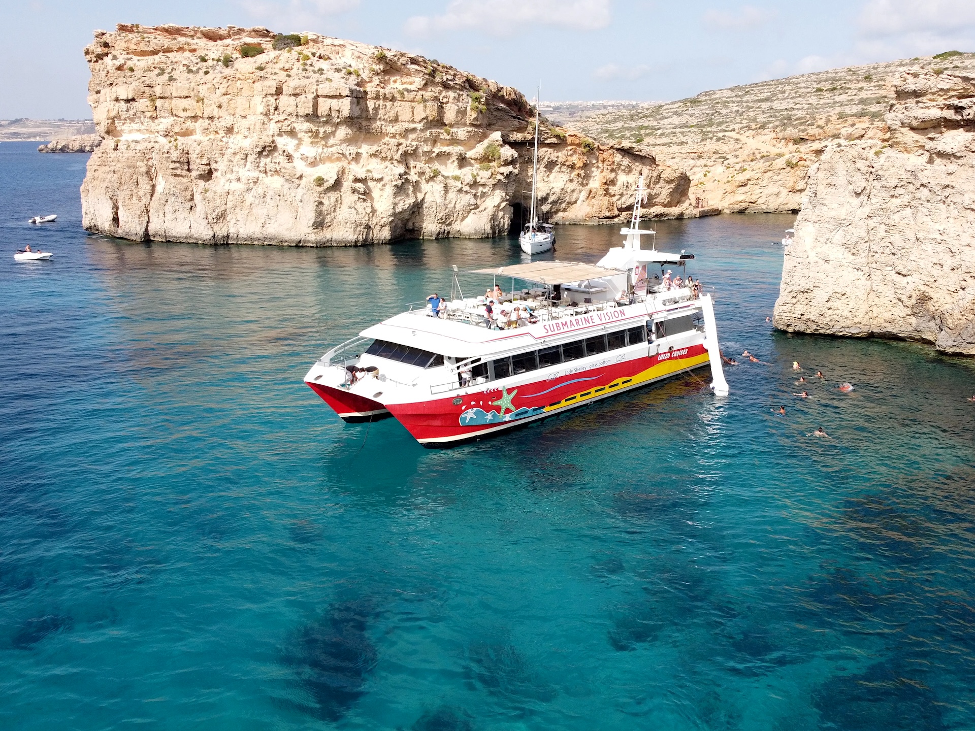 Barca da crociera nella Blue Lagoon Barca rossa e bianca in una cala intorno a Comino