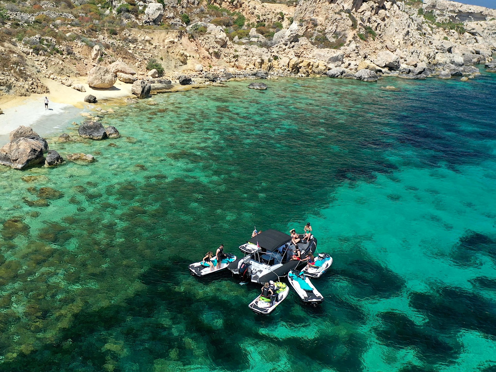 Jet ski alla Blue Lagoon Quattro jet ski e una barca sulla riva di Comino