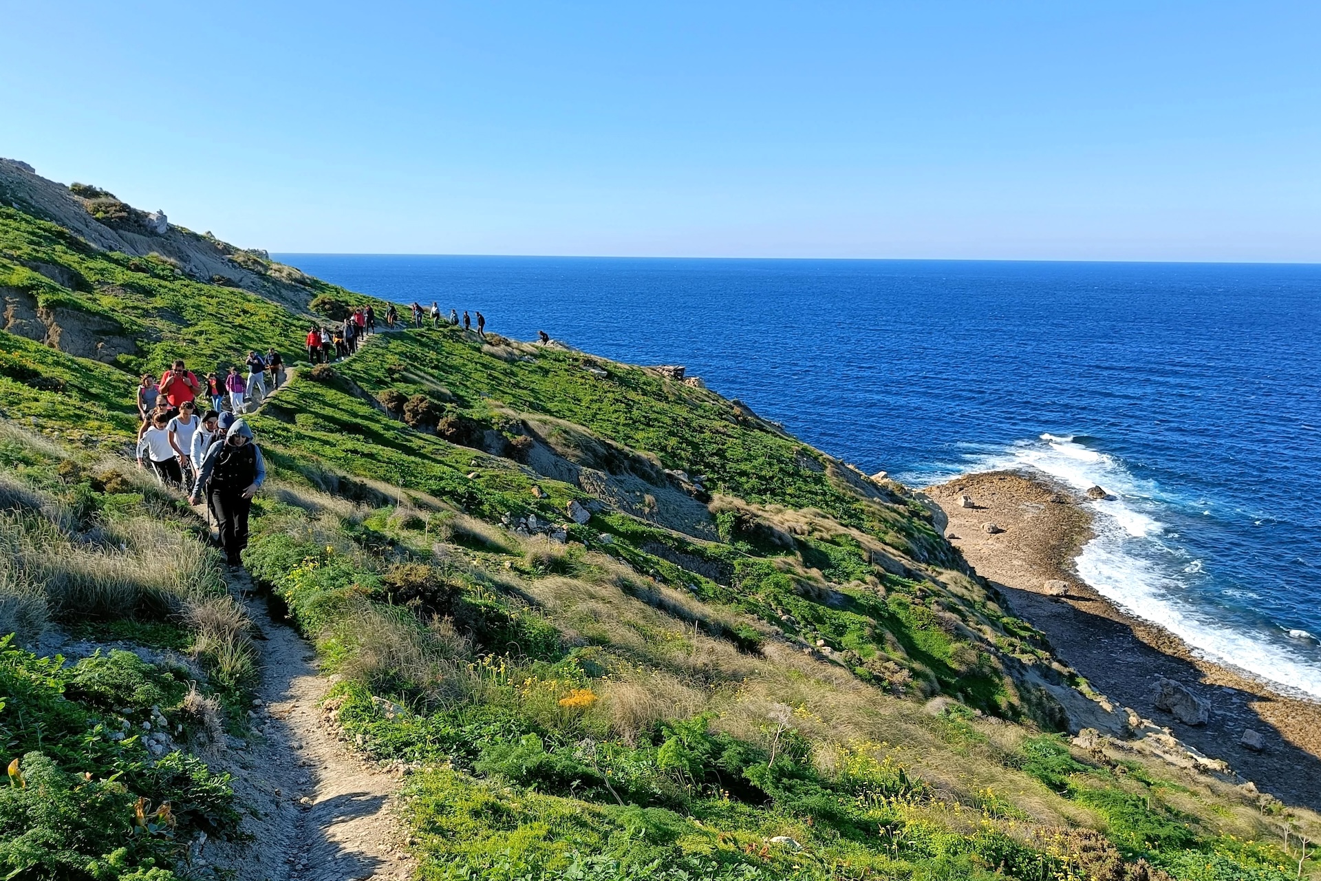 Groupe de personnes en randonnée sur les falaises de Mistra Bay
