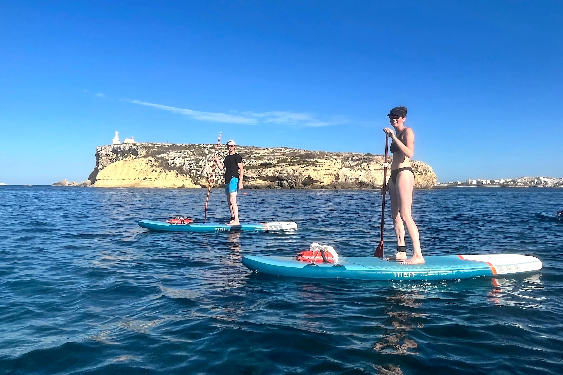 Un homme et une femme sur des stand up paddle devant l'île de St Paul's à Malte