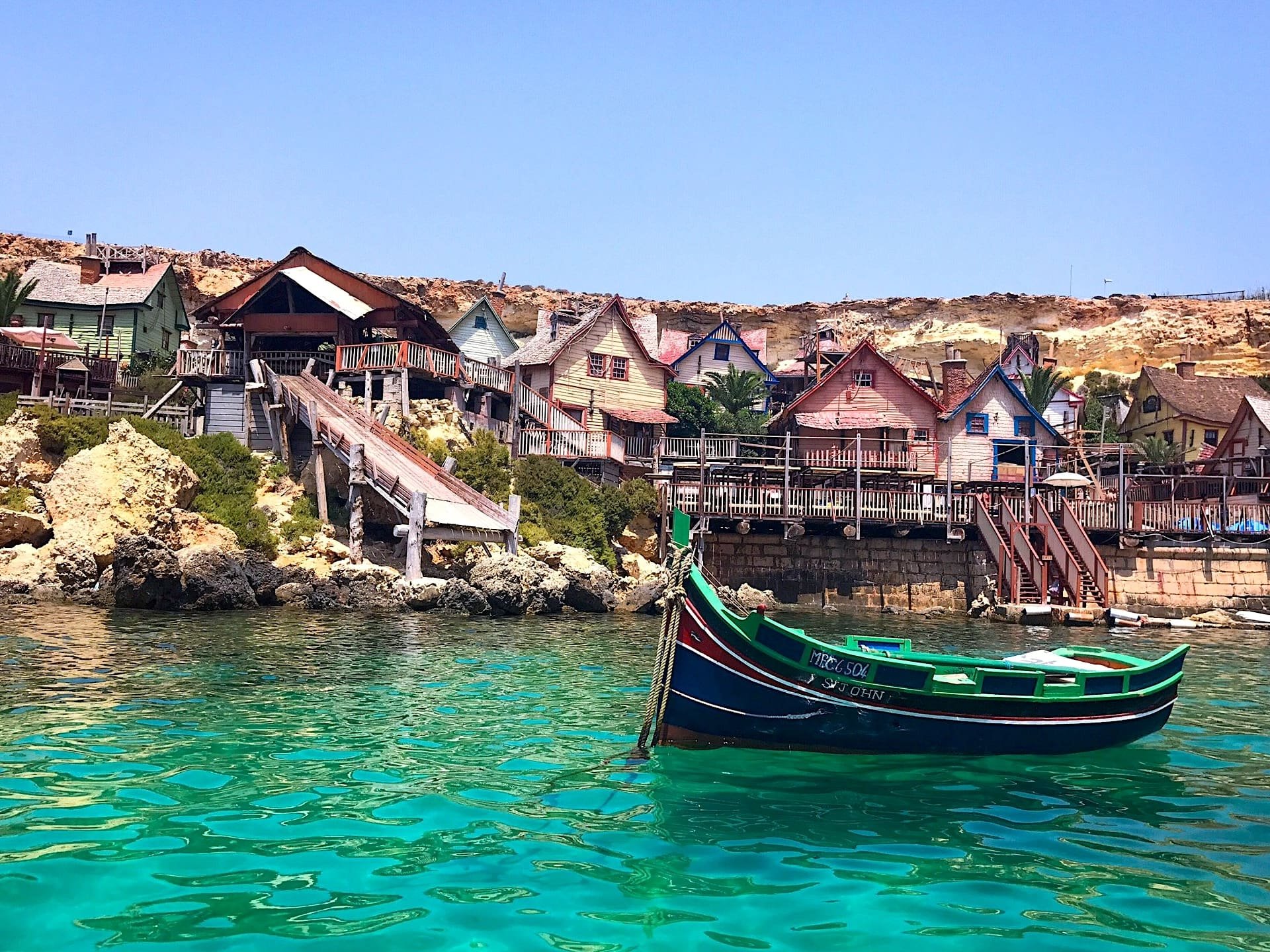 Barco no Popeye Village Barco na baía de Anchor Bay, diante do cenário do Popeye Village