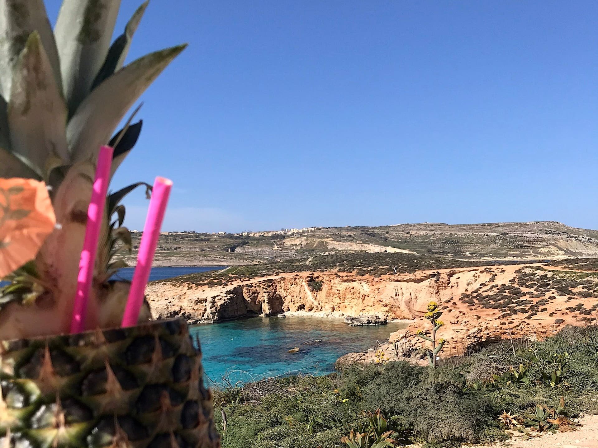 Cocktail ao sol de Malta Cocktail servido num ananás diante de uma lagoa turquesa