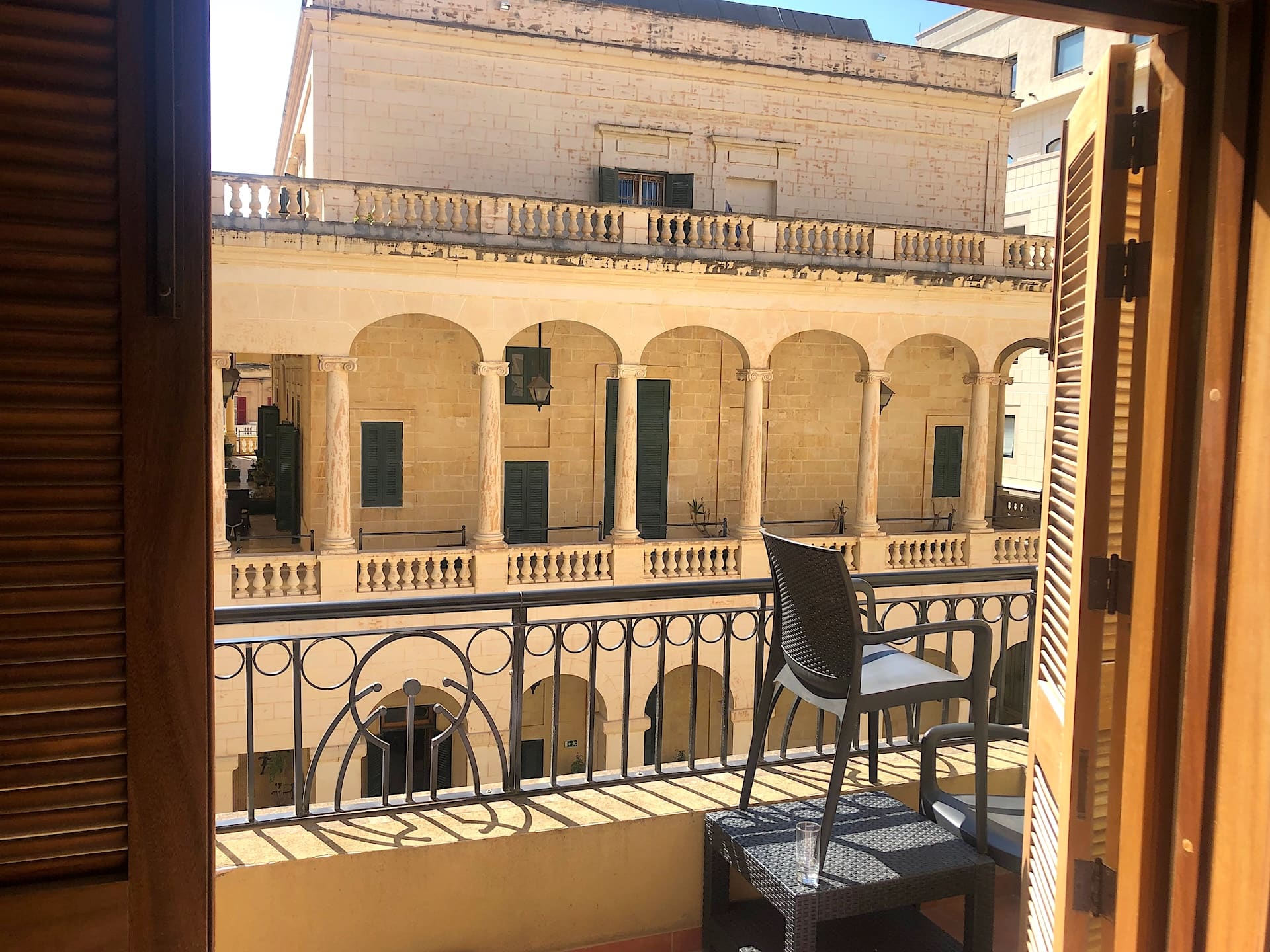 Varanda de um quarto do AX The Palace virada para um edifício histórico com arcadas em Sliema