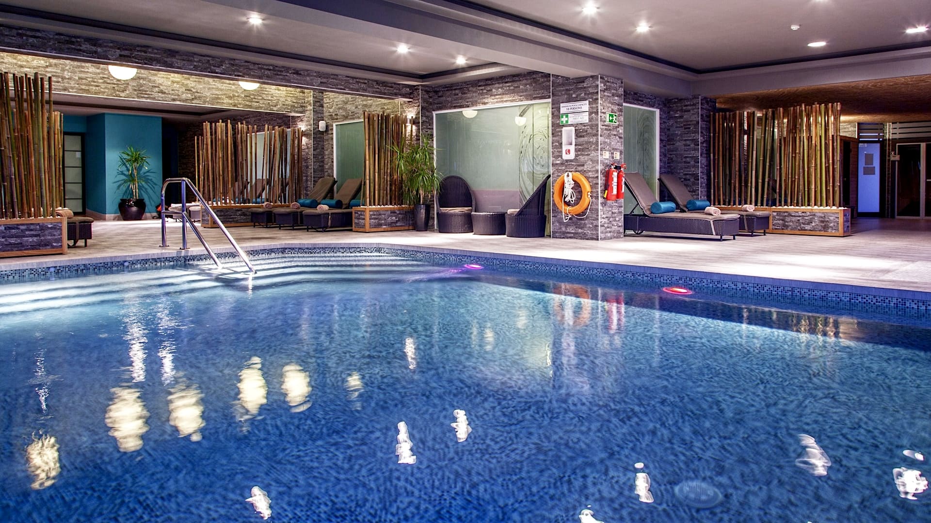 Piscina interior do AX The Palace com decoração em bambu e espreguiçadeiras