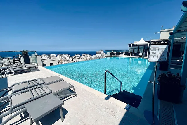 Piscine à débordement et transats sur le toit de l’AX The Palace en journée