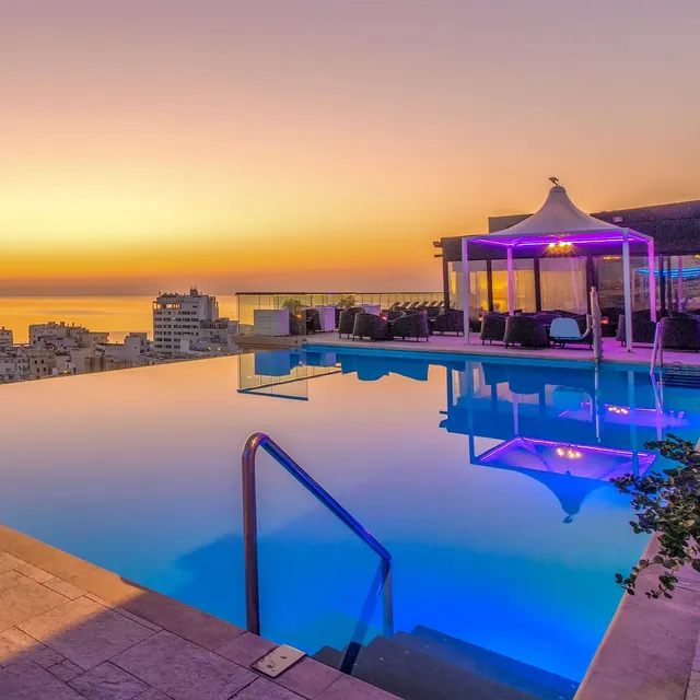 Piscine à débordement du toit de l’AX The Palace au coucher du soleil, avec vue sur la mer