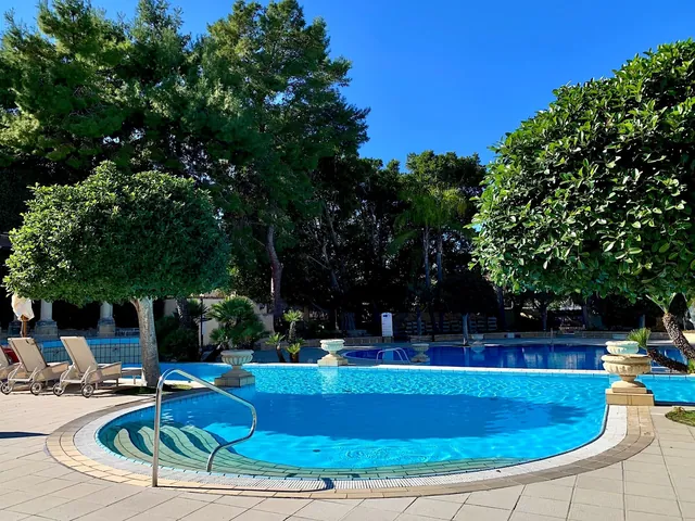 Piscine extérieure entourée d’arbres du Corinthia Palace à Malte