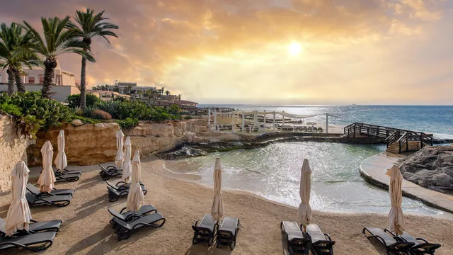 Crique de sable du Reef Club avec transats au Westin Dragonara Resort