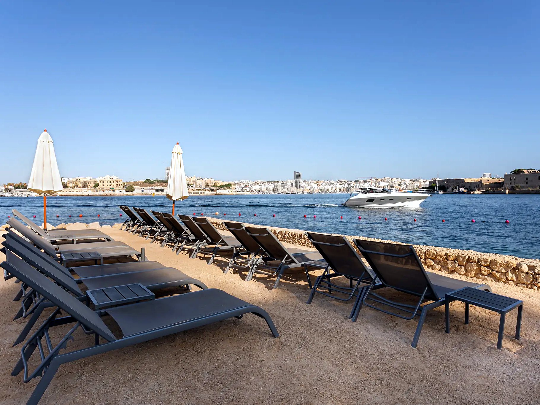 Lettini allineati sulla spiaggia privata del Grand Hotel Excelsior sul porto di Marsamxett