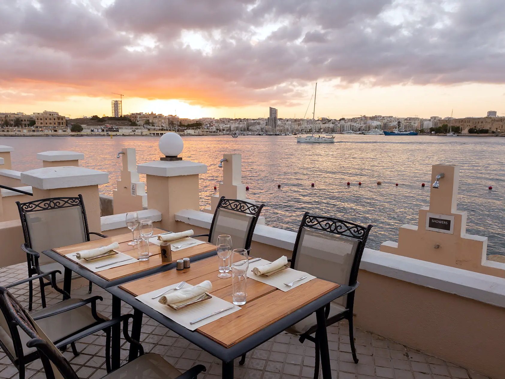 Tavolo apparecchiato in terrazza di fronte al porto al tramonto al Grand Hotel Excelsior di Malta