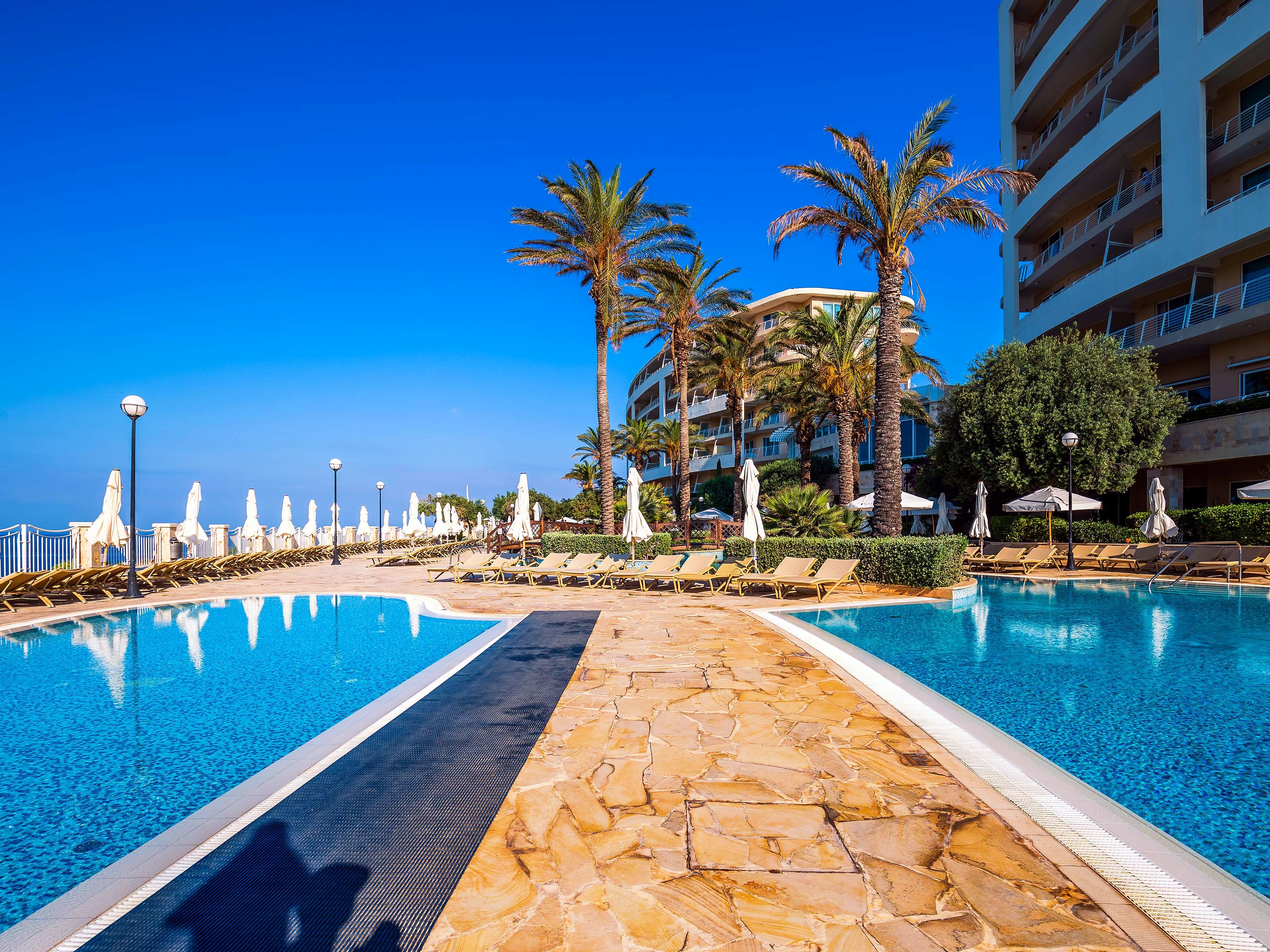 Piscina all’aperto circondata da palme al Radisson Blu Resort & Spa Golden Sands di Malta