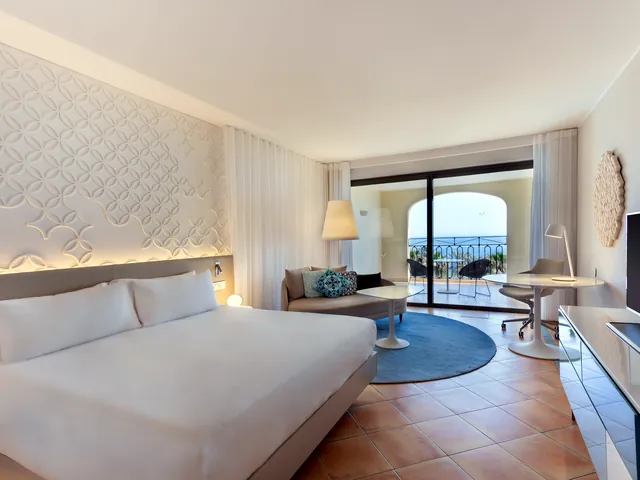 Chambre avec grand lit, coin salon et balcon vue mer au Hilton Malta