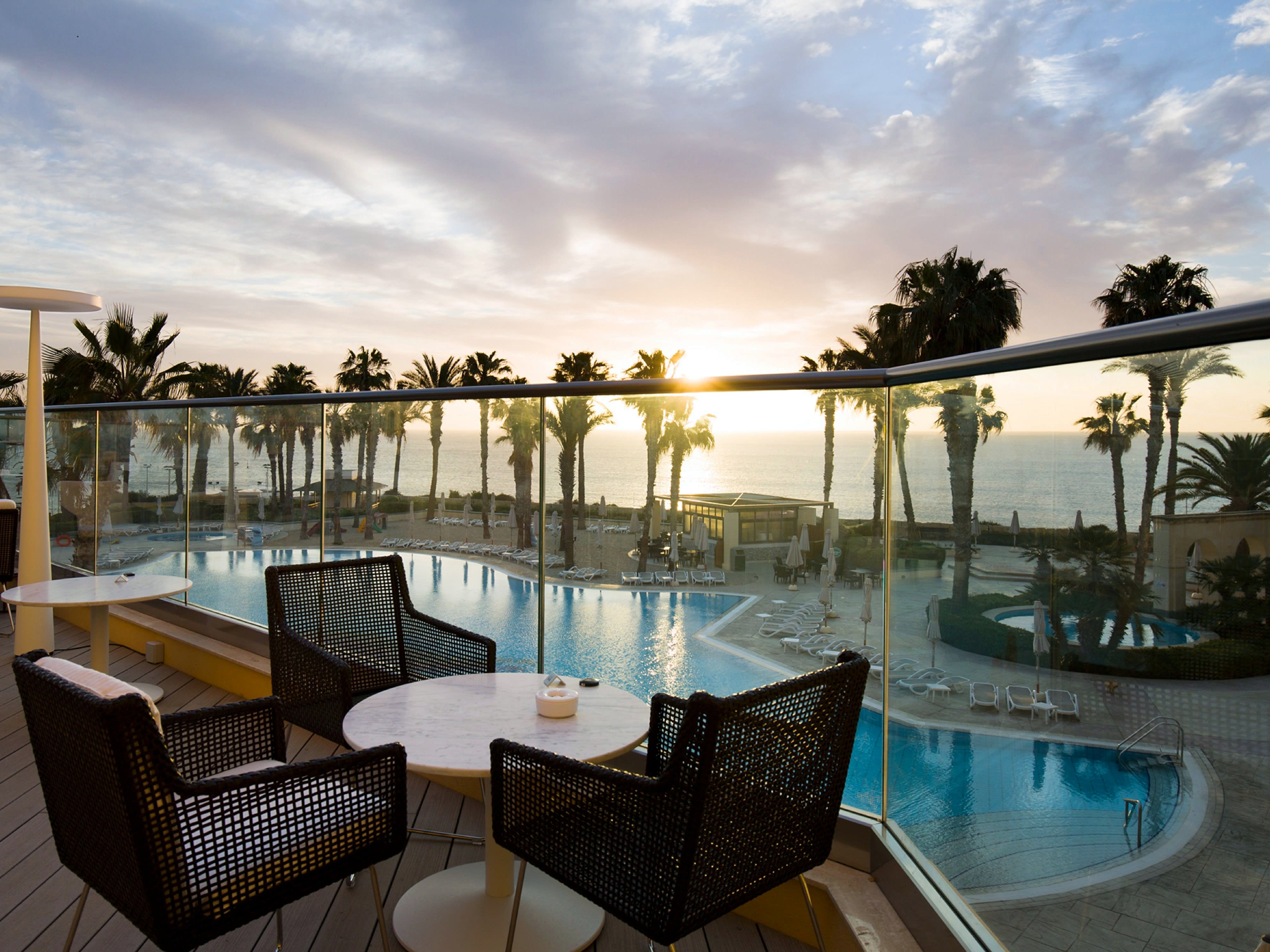 Terrazza della Vista Lounge con vista sulla piscina e sul mare al tramonto all’Hilton Malta