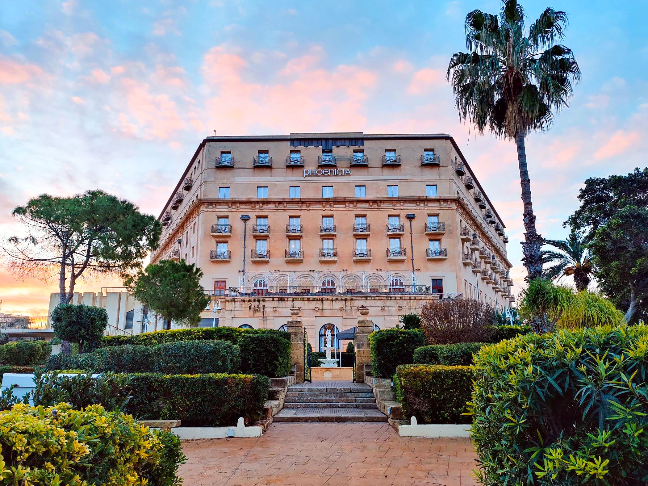 Facciata art déco di The Phoenicia Malta all’alba, vista dai suoi giardini a Floriana