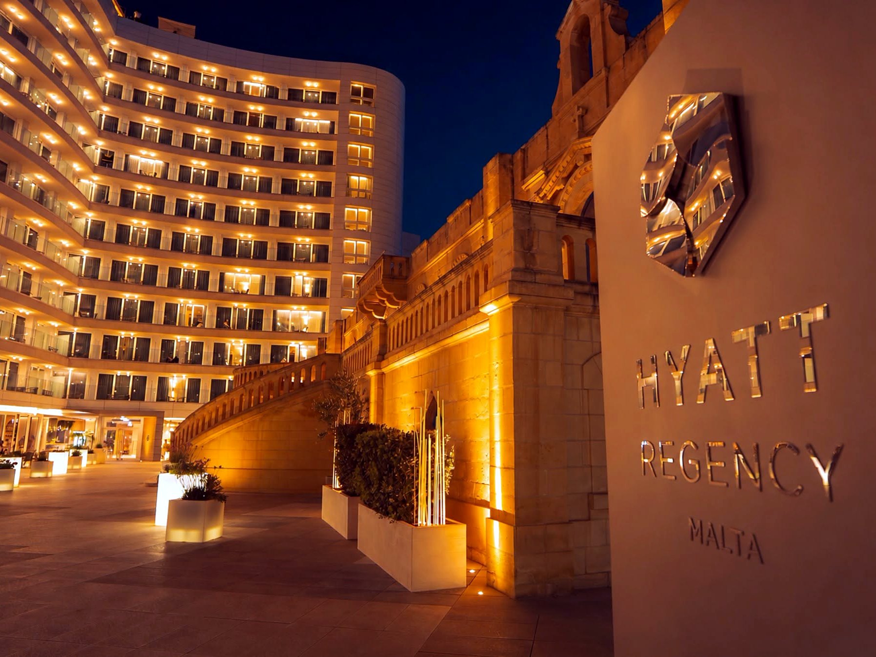 Facciata illuminata e insegna dell’Hyatt Regency Malta di notte