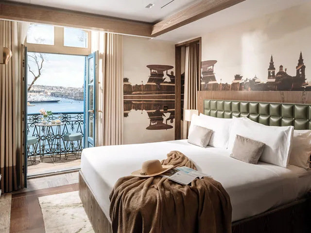Lit double d’une suite avec balcon ouvert sur le Grand Port à l’Iniala Harbour House de La Valette