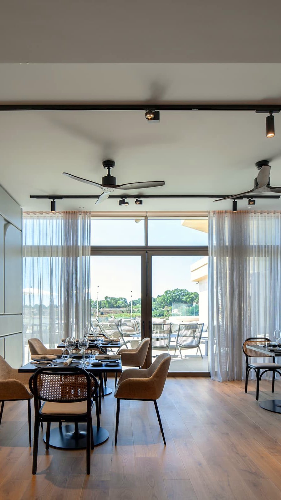 Sala luminosa del ristorante The Griffin Brasserie al Verdala Wellness Hotel AX Privilege, con tavoli apparecchiati e vetrata