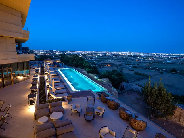 Piscine à débordement éclairée de nuit du Verdala Wellness Hotel AX Privilege, face aux lumières de la campagne maltaise