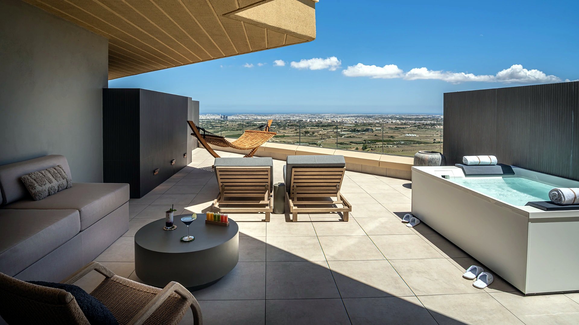 Terrazza di una junior suite del Verdala Wellness Hotel AX Privilege con vasca idromassaggio, lettini e amaca di fronte alla valle