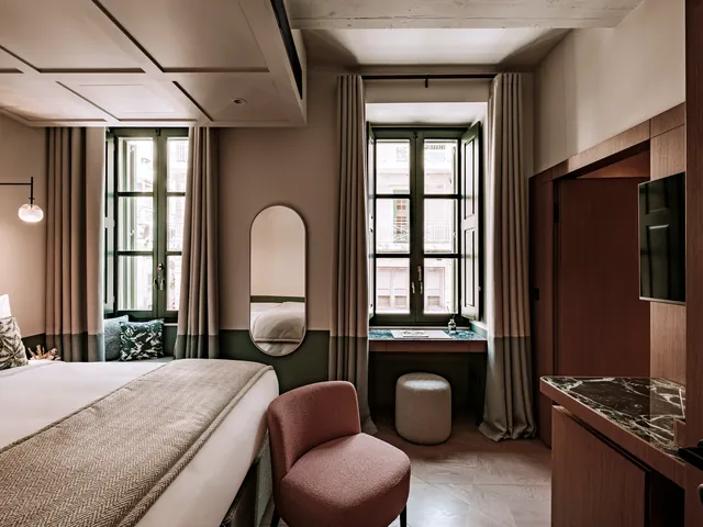 Chambre Deluxe du Romègas Hotel avec grand lit, boiseries et deux fenêtres sur les rues de La Valette