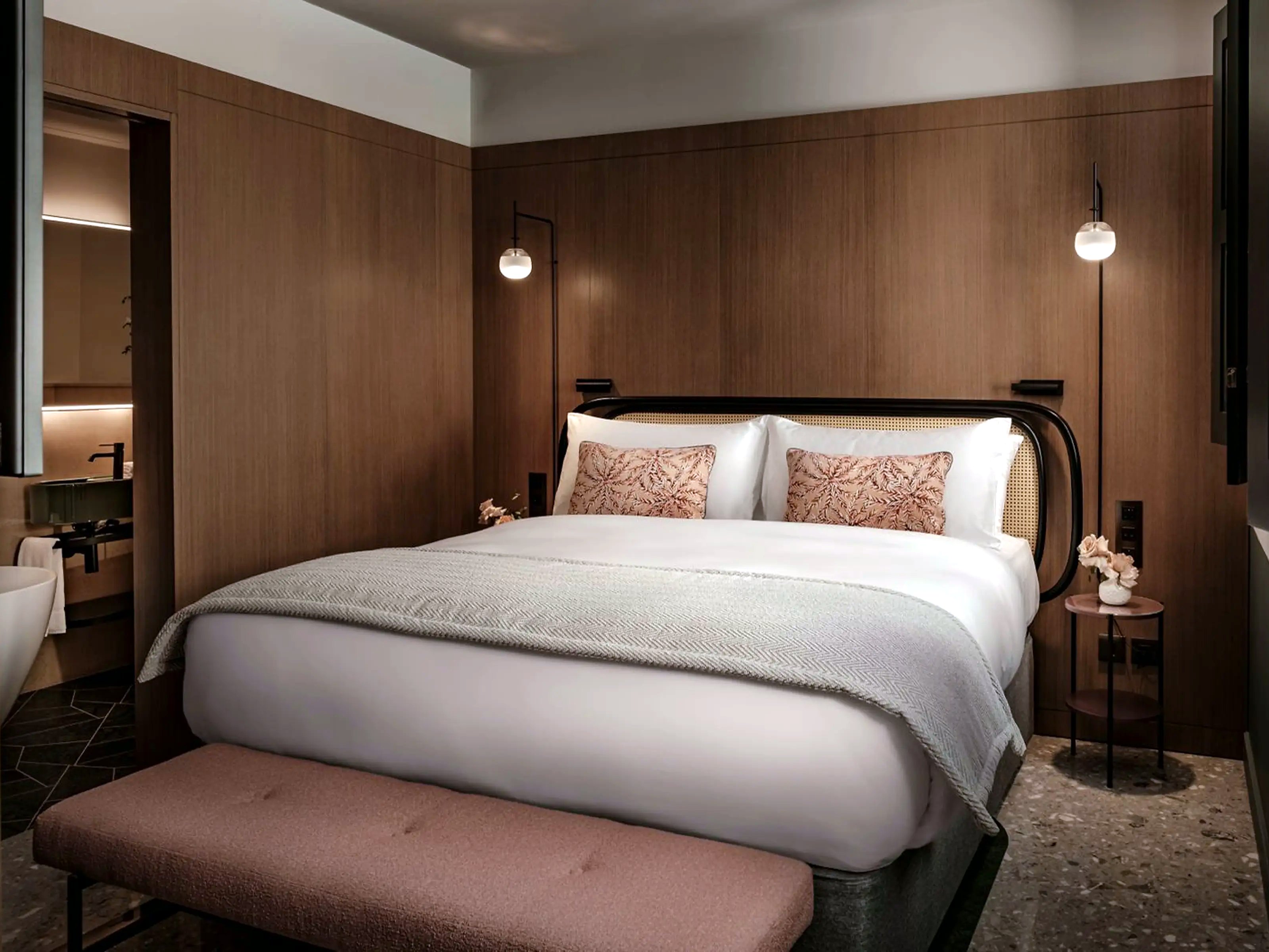 Quarto Executive do Romègas Hotel com cama grande, parede em madeira escura e chão em terrazzo