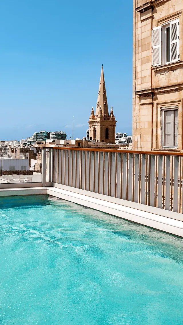 Bassin turquoise sur le toit-terrasse du Romègas Hotel, face au clocher de la pro-cathédrale Saint-Paul de La Valette