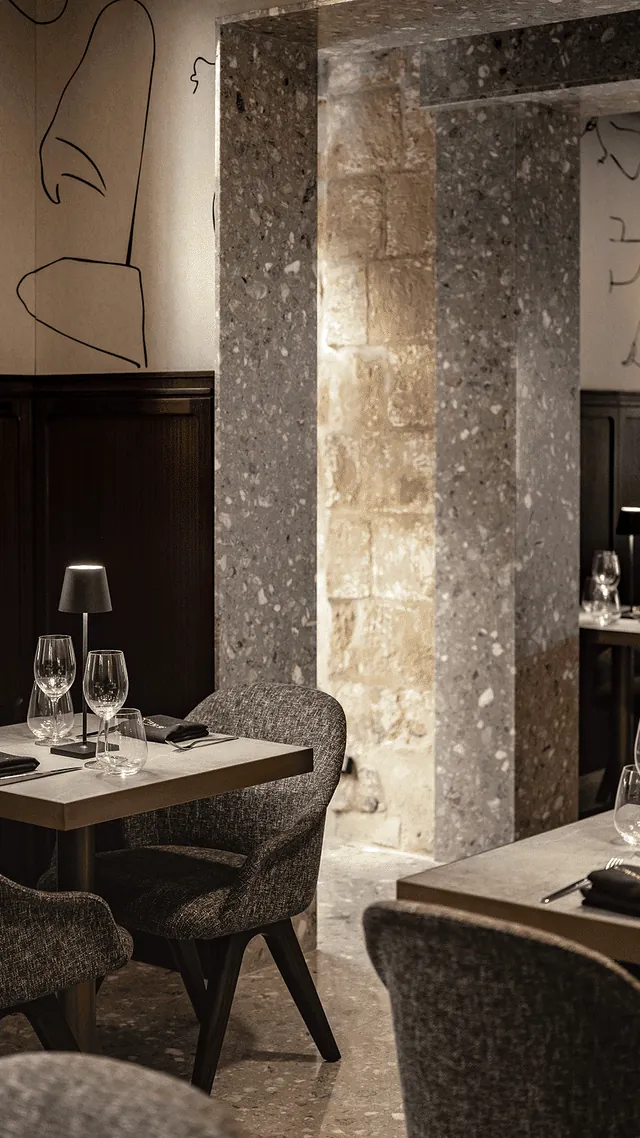 Tables dressées dans une salle aux murs de pierre du restaurant Caviar & Bull au Romègas Hotel