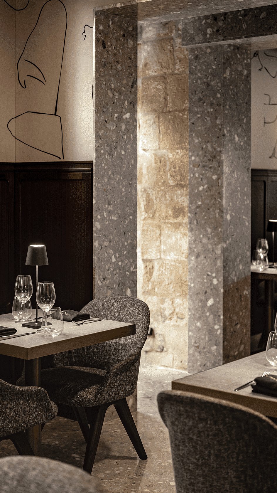 Mesas postas numa sala com paredes de pedra do restaurante Caviar & Bull no Romègas Hotel