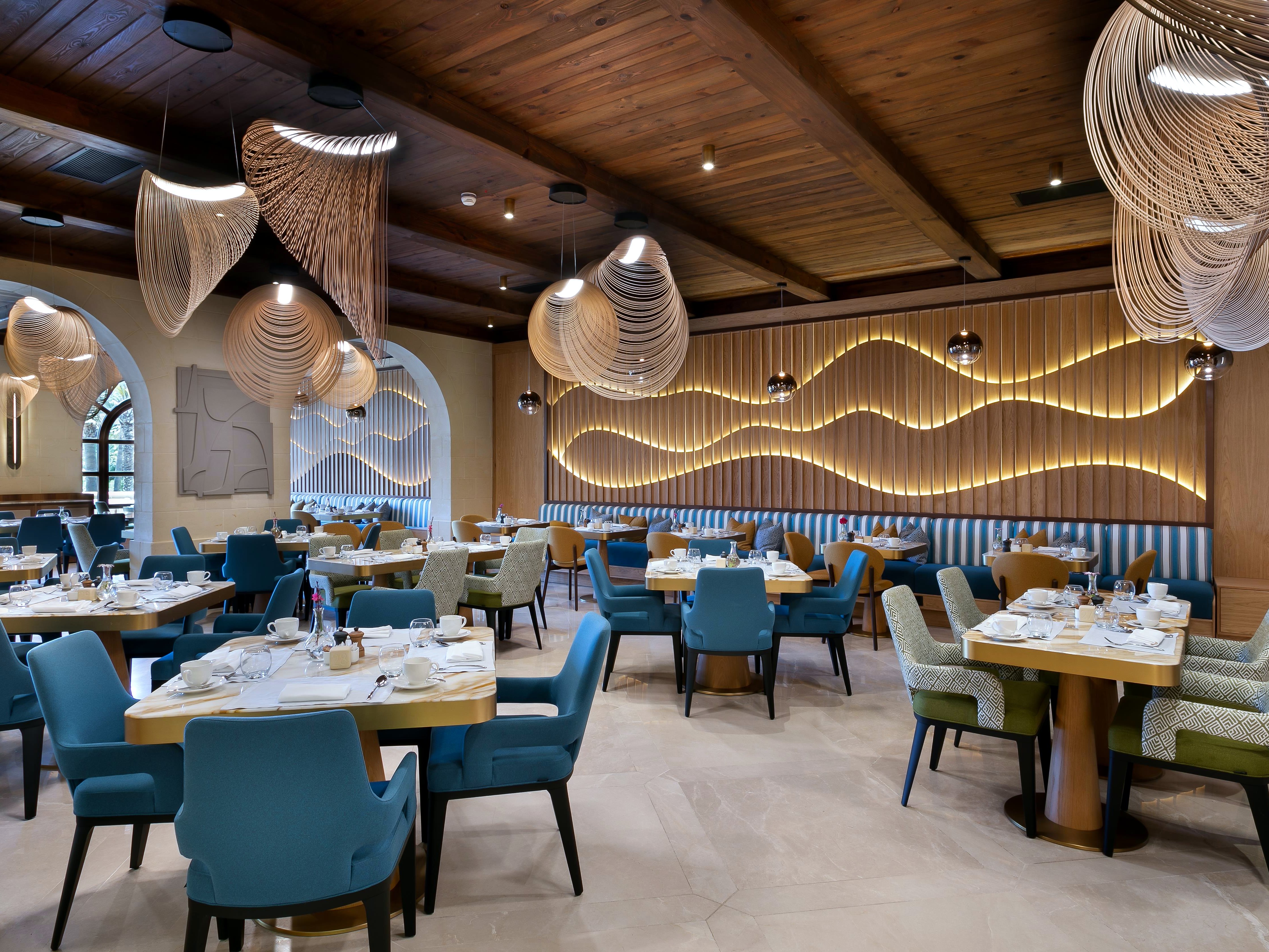 Sala del ristorante L’Ortolan con poltrone blu e lampade in vimini al Kempinski Hotel San Lawrenz
