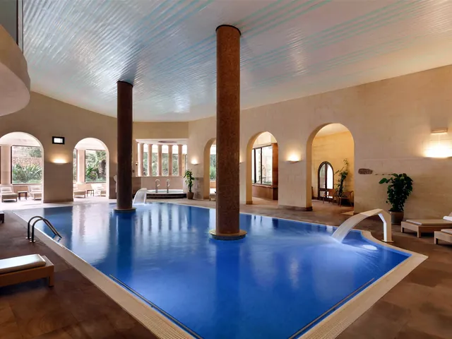 Piscine intérieure chauffée du spa avec colonnes et arcades en pierre au Kempinski Hotel San Lawrenz