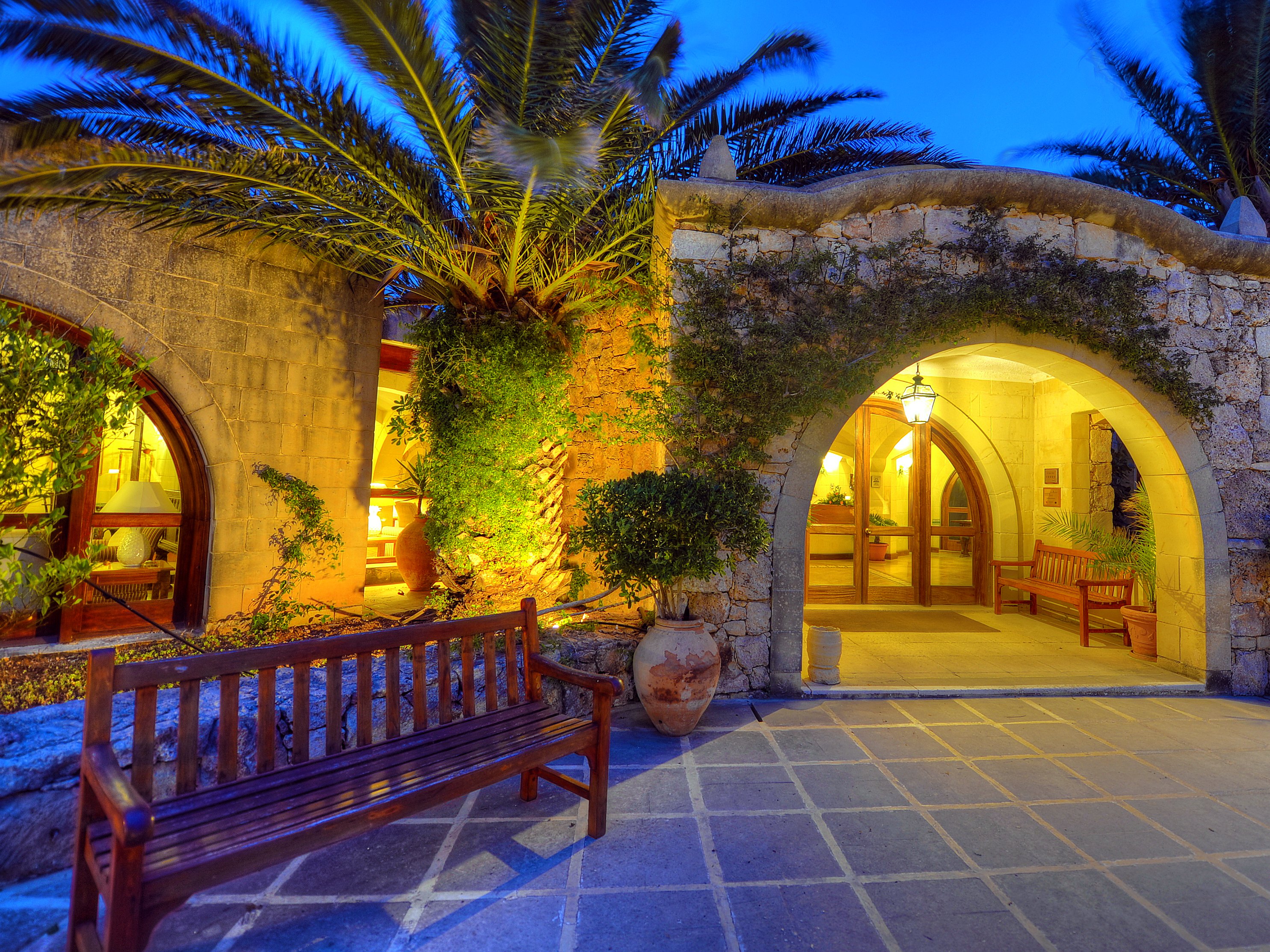 Ingresso in pietra a volta dell’hotel Ta’ Ċenċ & Spa a Gozo, illuminato al calar della notte sotto le palme