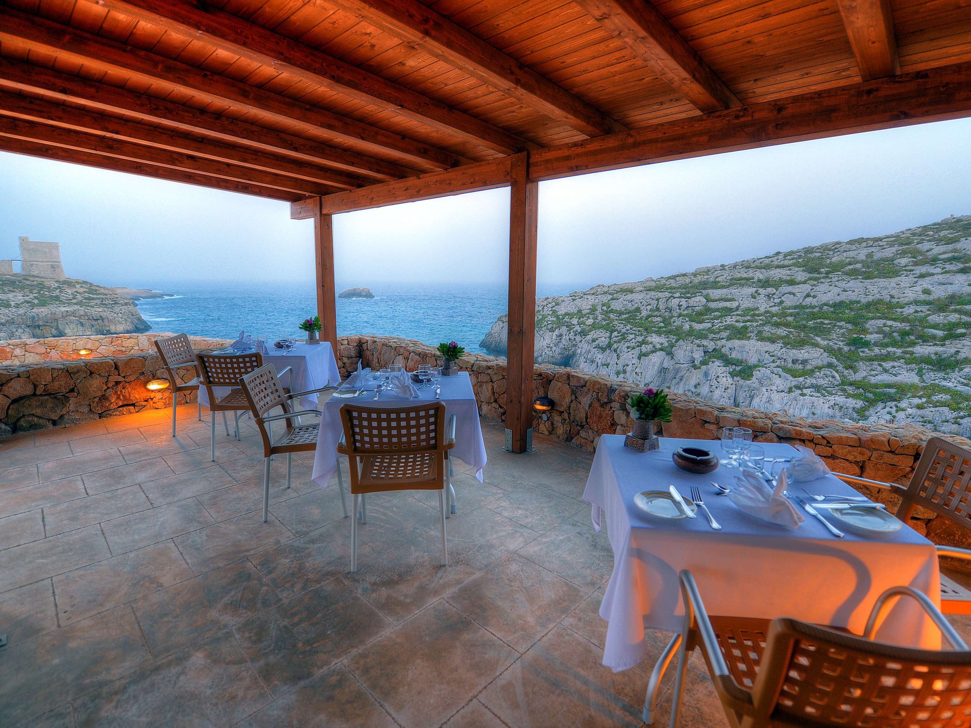 Terrazza coperta del ristorante Il-Kantra di fronte al mare e alla torre di Mġarr ix-Xini, lido dell’hotel Ta’ Ċenċ & Spa