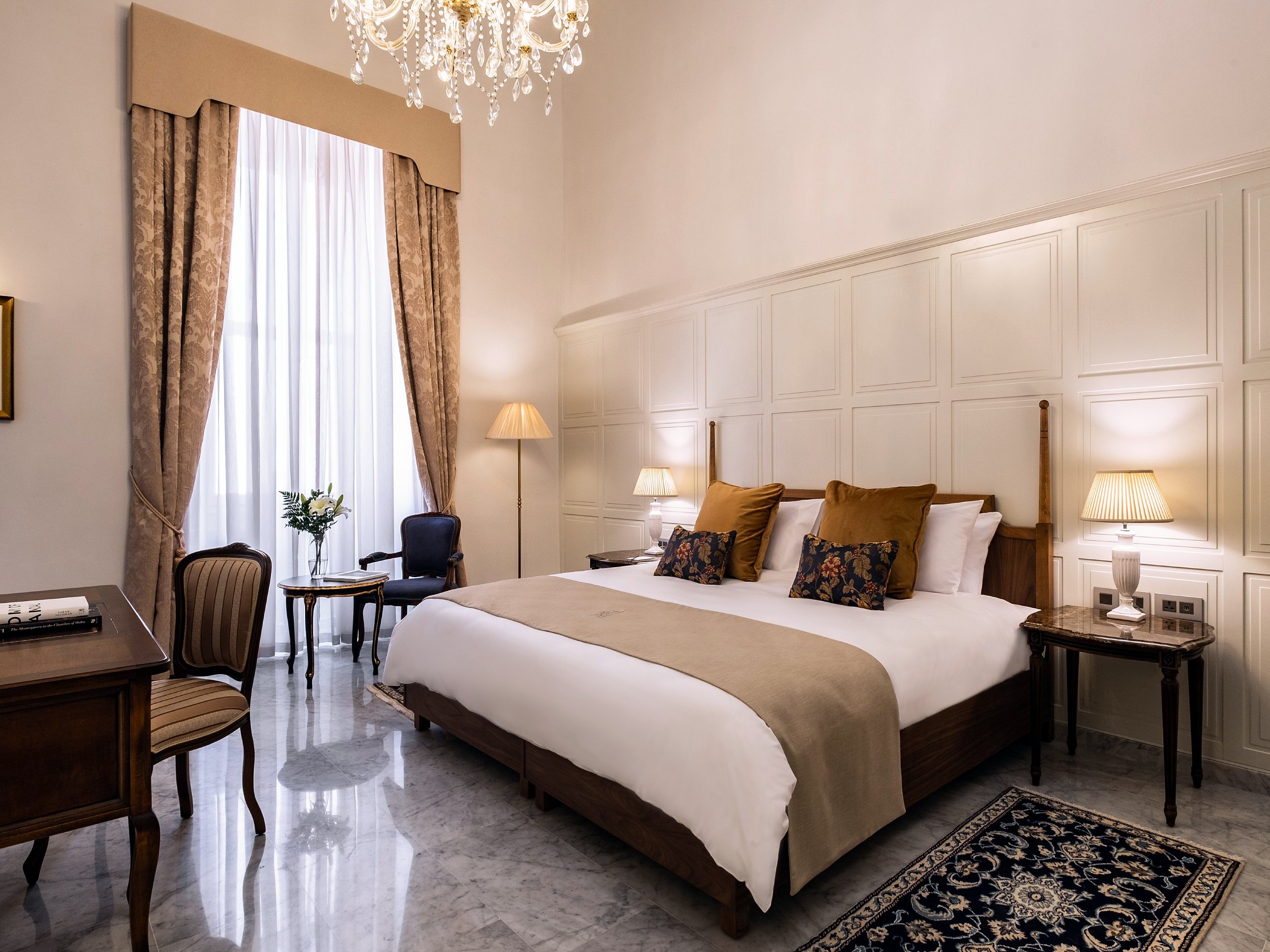 Suite duplex del Palais Le Brun con ampio letto matrimoniale, lampadario di cristallo, boiserie bianche e pavimento in marmo