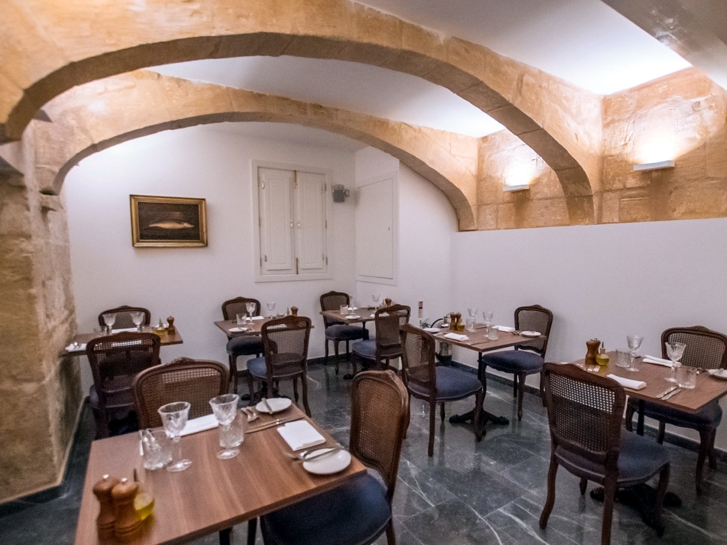 Sala a volta in pietra del ristorante del Palais Le Brun con tavoli apparecchiati e sedie in paglia di Vienna