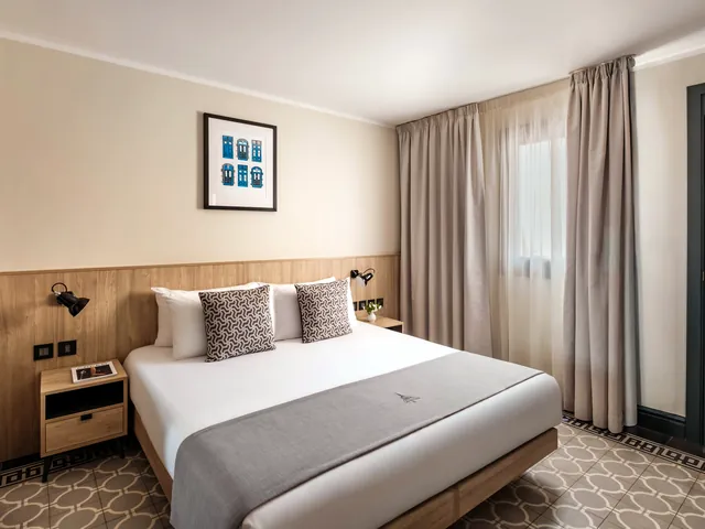 Chambre Double de La Falconeria avec grand lit, fenêtre à rideaux et sol en carreaux de ciment