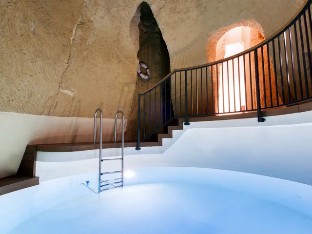 Piscine intérieure de La Falconeria aménagée dans un ancien puits creusé dans la roche, avec escalier en colimaçon