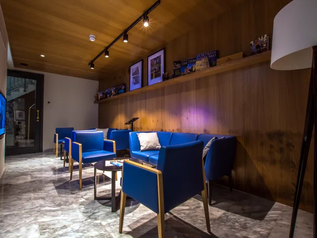 Salon de La Falconeria avec fauteuils bleus, boiseries et éclairage sur rail