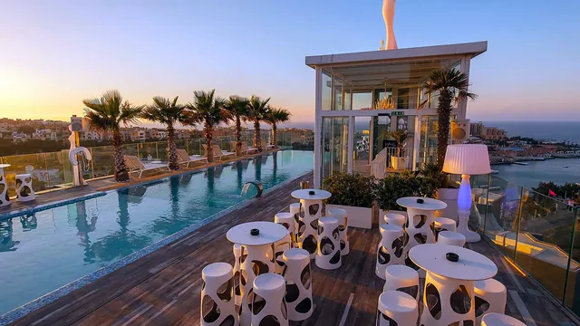 Piscine à débordement et bar vitré sur le toit du H Hotel au coucher du soleil, ouverts aux clients du Hugo’s Boutique Hotel