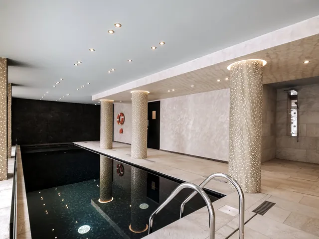 Piscine intérieure chauffée du spa de l’Urban Valley Resort & Spa, entre colonnes en mosaïque et éclairage tamisé