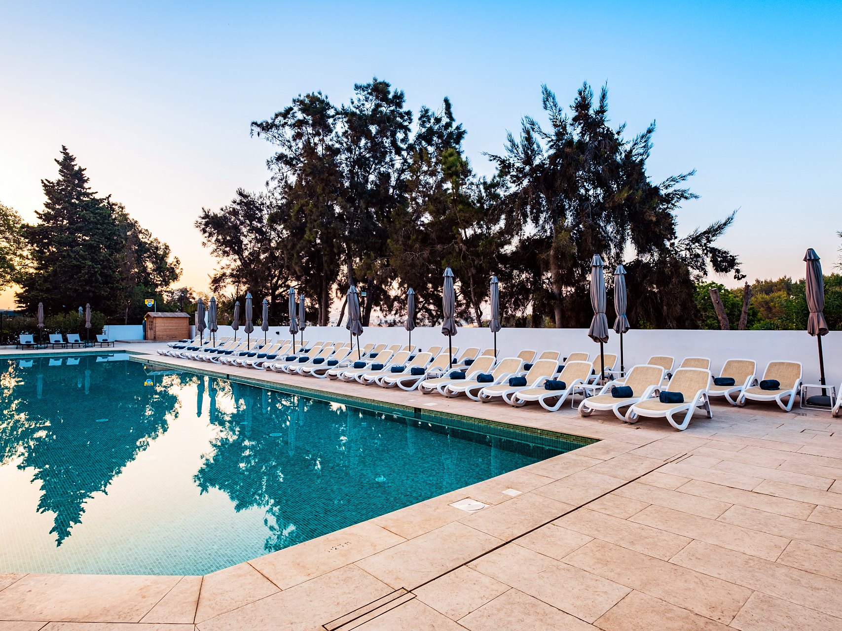Urban Valley Resort & Spa - Terraza de la piscina Terraza de la piscina del Urban Valley Resort & Spa al atardecer, con tumbonas alineadas bajo los árboles del valle