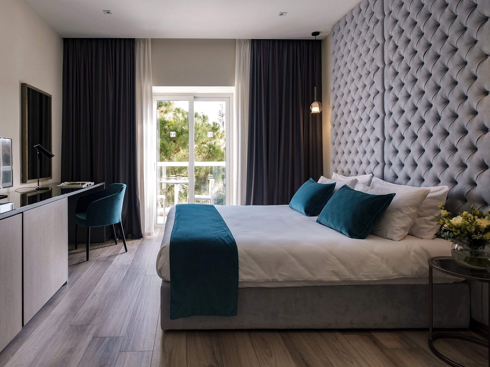 Habitación superior del Urban Valley Resort & Spa con cama de matrimonio, cabecero acolchado, escritorio y puerta acristalada al balcón