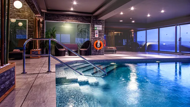 Piscine intérieure de l’AX The Victoria avec ses baies vitrées et son coin détente