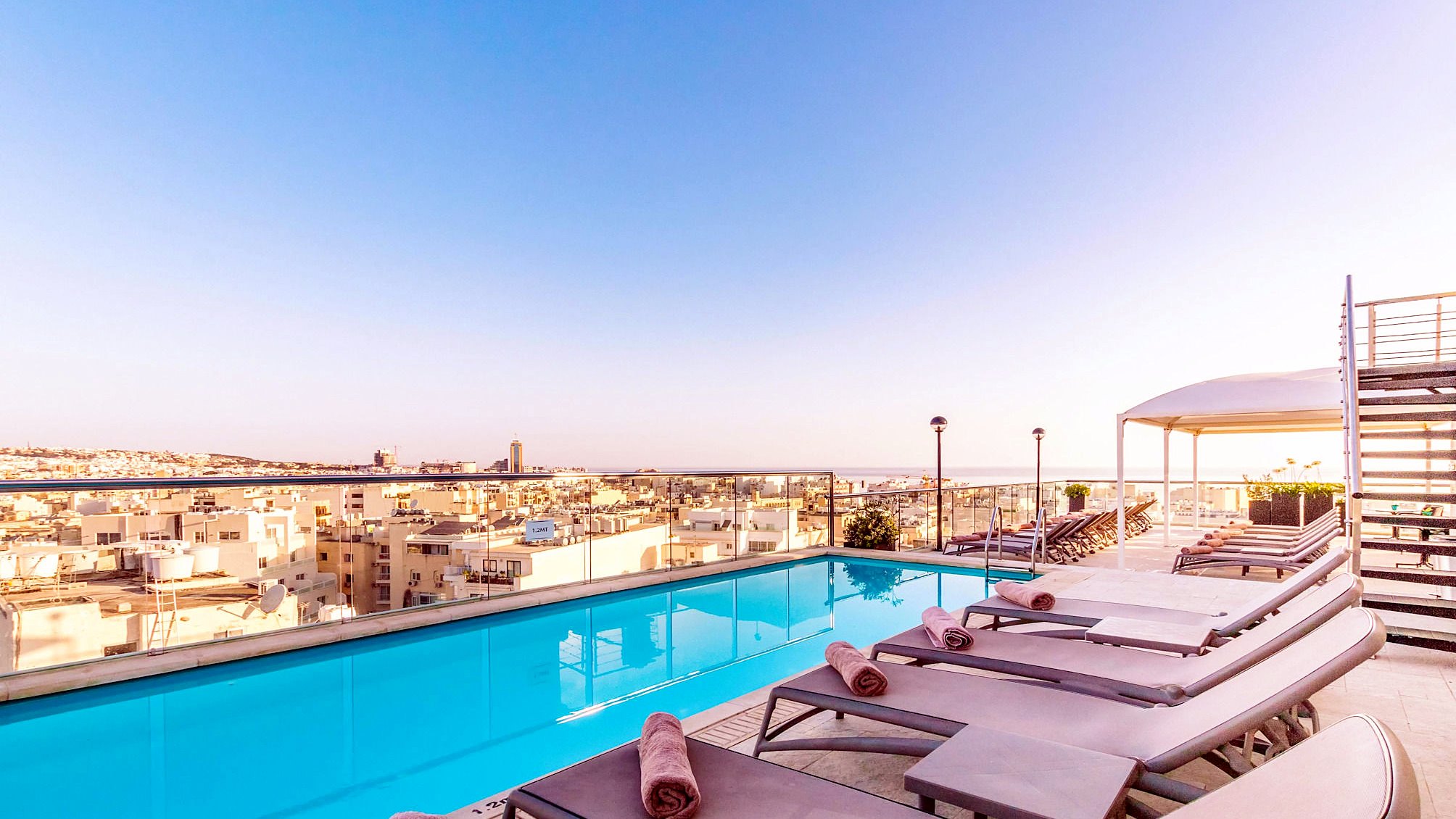 AX The Victoria - Piscina sul tetto Piscina sul tetto dell’AX The Victoria circondata da lettini, con vista sui tetti di Sliema
