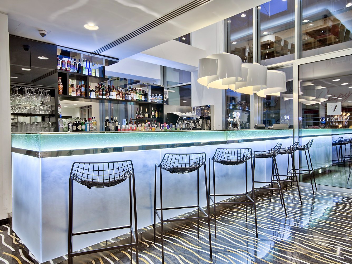 Bancone luminoso e sgabelli del lounge bar nella hall dell’Hotel Valentina a St Julian’s