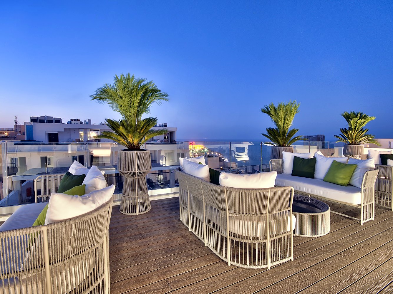 Salotto all’aperto con divani bianchi e palme sulla terrazza panoramica dell’Hotel Valentina a St Julian’s