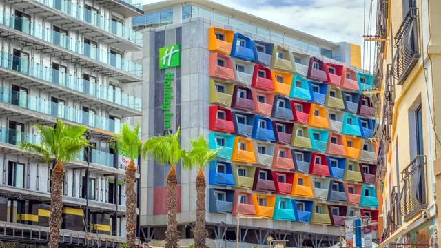 Façade aux balcons multicolores du Holiday Inn Express Malta, bordée de palmiers, à St Julian’s