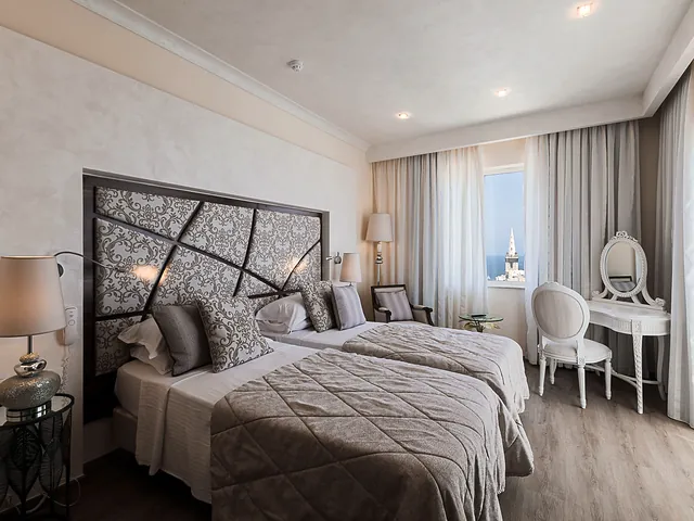 Chambre Deluxe vue mer de l’Osborne Hotel avec deux lits, coiffeuse et fenêtre sur le dôme de l’église des Carmes