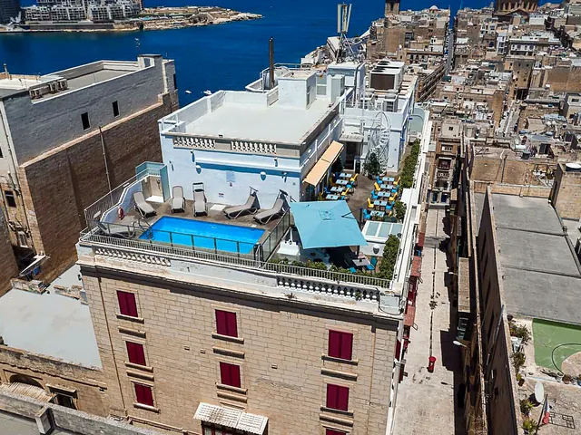 Vue aérienne de l’Osborne Hotel à La Valette, avec sa piscine sur le toit et le port de Marsamxett en arrière-plan