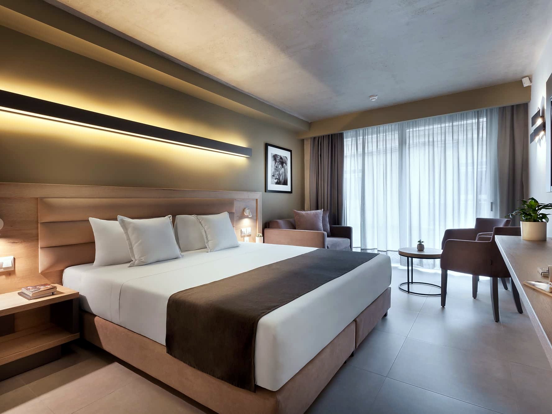 Chambre de l’Azur Hotel by ST Hotels avec grand lit, bureau, fauteuil et baie vitrée voilée