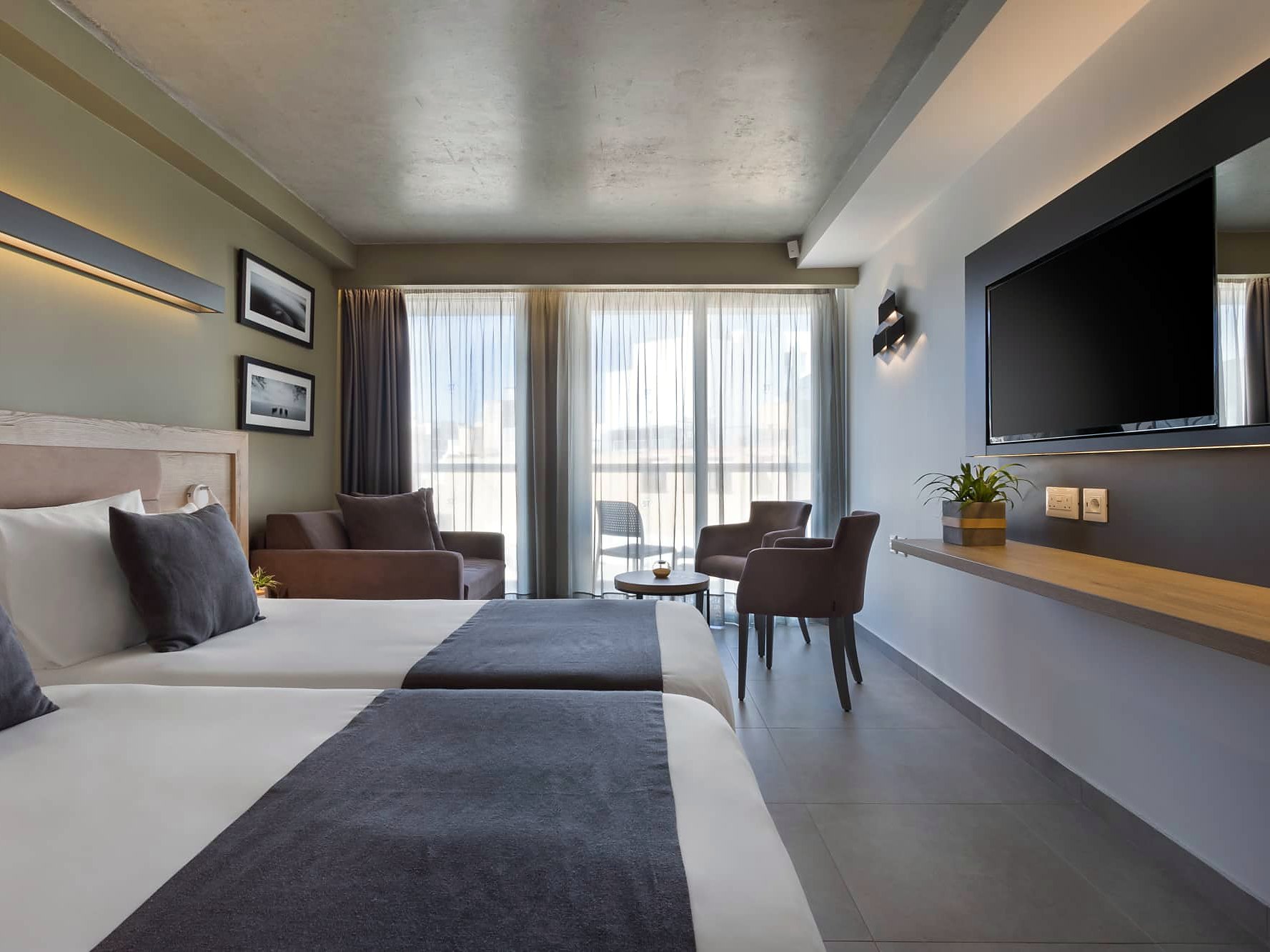 Chambre Standard de l’Azur Hotel by ST Hotels avec deux lits, télévision murale et coin salon